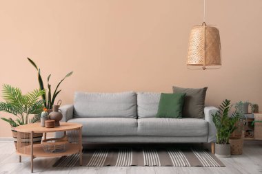 İçinde rahat gri kanepe, sehpa ve ev bitkileri olan bir oturma odası.