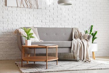 Parlak oturma odasının içinde, sehpanın üzerinde modern bir laptop var.