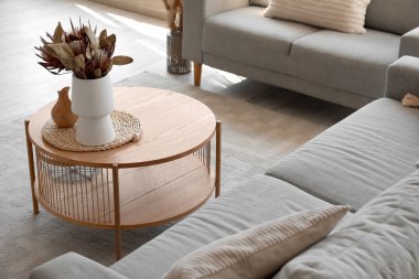 Sıcak gri koltuklar ve kahve masası. Oturma odasında kurutulmuş protea çiçekleri.