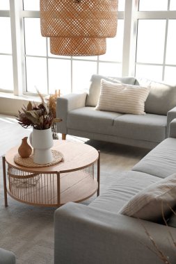 Sıcak gri koltuklar ve kahve masası. Oturma odasında kurutulmuş protea çiçekleri.