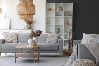 Oturma odasında kurutulmuş protea çiçekleri olan rahat gri kanepe ve kahve masası.