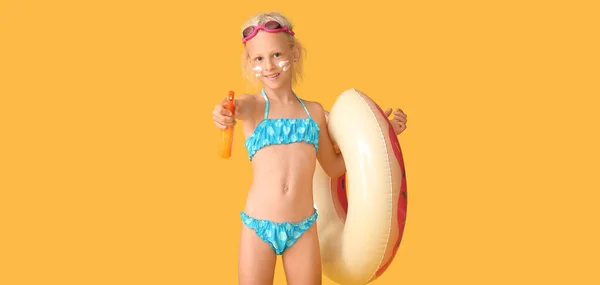 Menina Pequena Com Creme Protetor Solar Anel Inflável Fundo Amarelo — Fotografia de Stock