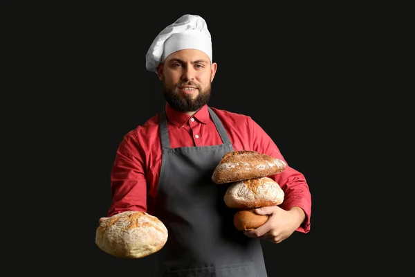 Male Baker Loaves Fresh Bread Dark Background — Stock Photo, Image