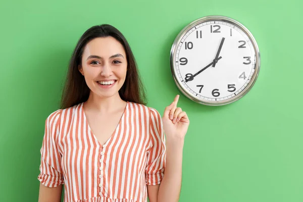 Young Woman Pointing Clock Green Wall — Stock Photo, Image