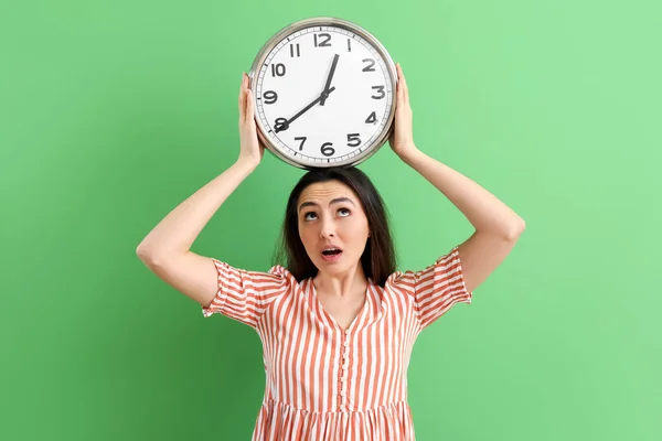 Shocked Young Woman Wall Clock Green Background — Stock Photo, Image
