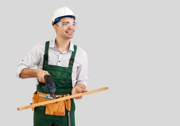 Young Carpenter Sawing Wooden Plank Grey Background — Stock Photo, Image