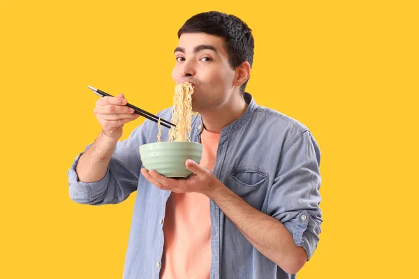 Young Man Eating Chinese Noodles Yellow Background — Stock fotografie
