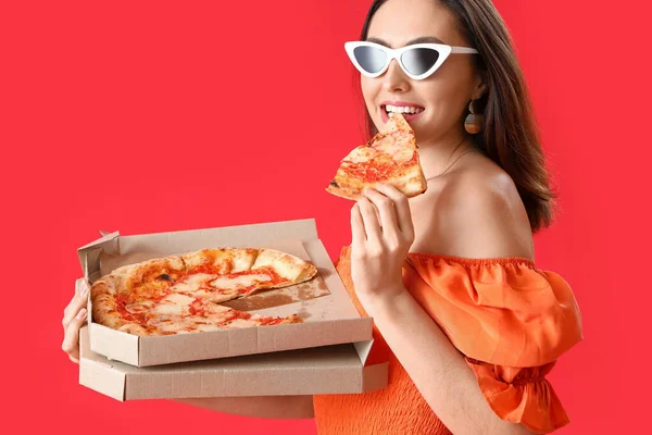Piękna Kobieta Okularach Przeciwsłonecznych Jedząca Smaczną Pizzę Czerwonym Tle — Zdjęcie stockowe