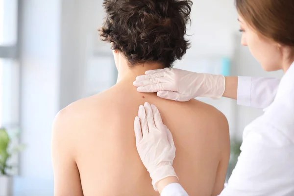 皮肤科医生在诊所检查年轻人背上的痣 — 图库照片