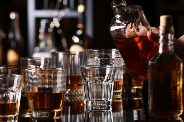 女人在酒吧的桌子上把美味的朗姆酒从瓶子倒进玻璃杯里 — 图库照片