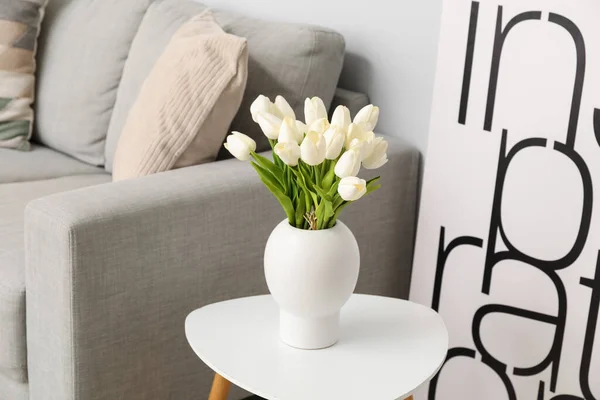 灰色のソファの近くのテーブルの上に美しいチューリップの花の花瓶 — ストック写真