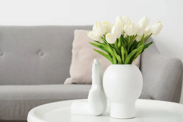灰色のソファの近くのテーブルの上に美しいチューリップの花の花瓶 — ストック写真