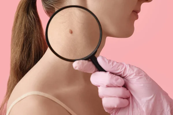 Dermatólogo Examinando Topo Mujer Joven Con Lupa Sobre Fondo Rosa — Foto de Stock