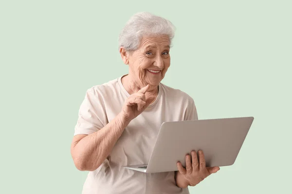 stock image Senior woman with laptop on green background