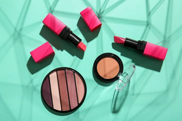Composition with different cosmetic products and shadows on color background