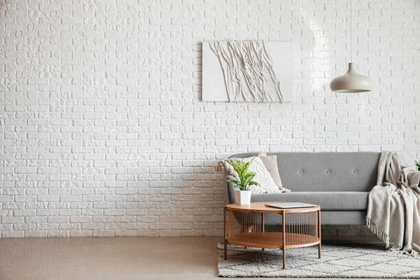Beyaz Tuğla Duvarın Yanında Modern Dizüstü Bilgisayarı Olan Gri Kanepe — Stok fotoğraf