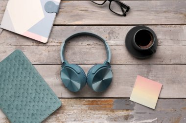 Gri ahşap arka planda defter ve gözlüklü modern mavi kulaklıklar.