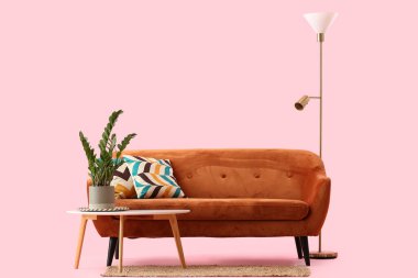 Pembe arka planda yastıkları olan rahat kahverengi kanepe.