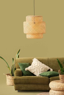 Sıcak kanepe, hasır puflar ve yeşil arka planda ev bitkileri.