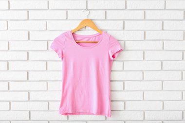 Beyaz tuğla duvarda asılı pembe tişört