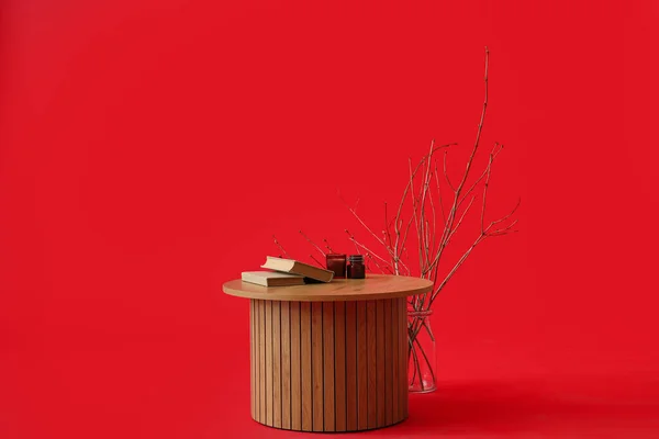 Wooden coffee table with books and candles on red background