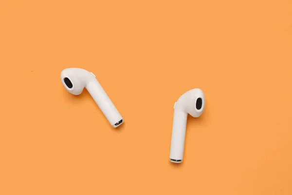 Modern white earphones on beige background