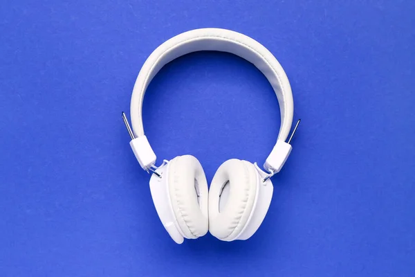 现代在蓝色背景上的白色耳机 — 图库照片