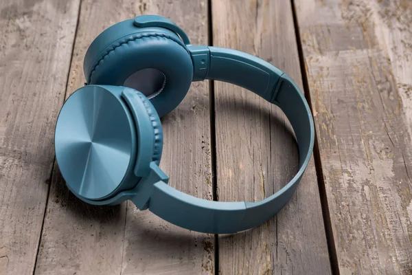 灰色木制背景的现代蓝色耳机 — 图库照片
