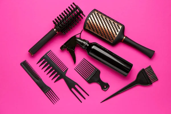 Hairdresser\'s brushes with spray on pink background