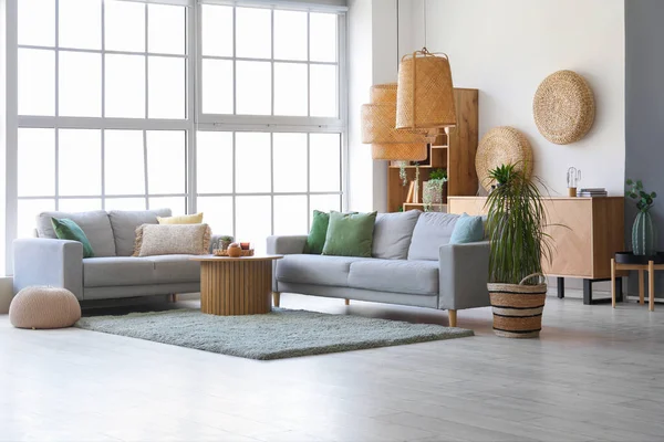 Interior of bright living room with cozy grey sofas and coffee table on soft carpet