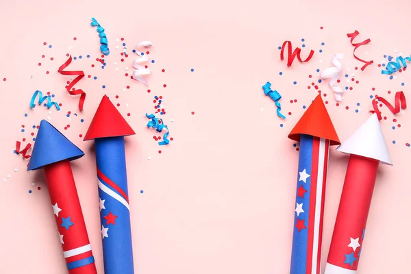 Firework rockets, confetti and serpentine for Independence Day on pink background