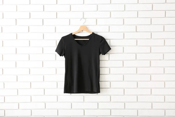 白いレンガの壁に吊るされた黒いTシャツ — ストック写真