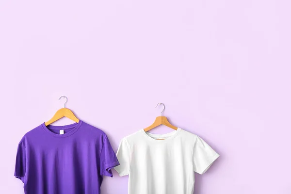 Purple and white t-shirts hanging on lilac wall