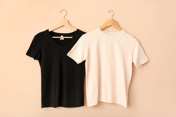 White and black t-shirts hanging on light wall