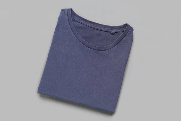 灰色の背景に青いTシャツを折ります — ストック写真