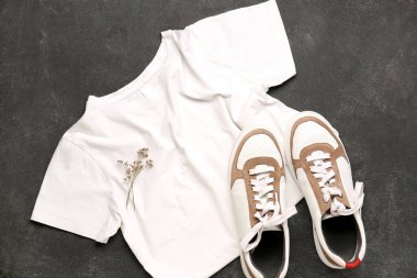 Siyah arka planda spor ayakkabılı ve çiçekli beyaz tişört