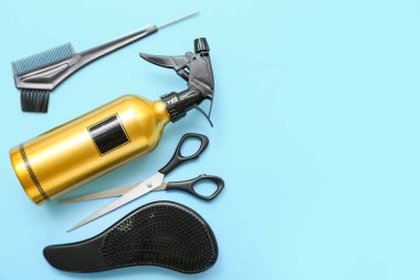 Mavi arka planda fırça ve makas ile saç spreyi