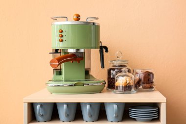 Kahve makineli masa, bej duvarın yanında aperatifler ve fincanlar