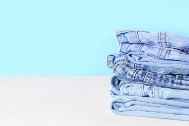 Mavi duvarın yanındaki masada kot pantolon yığını, yakın plan.