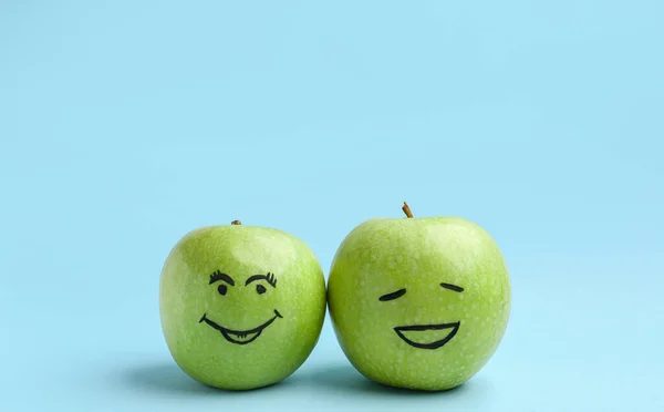 Apples with happy faces on blue background. Friendship Day celebration