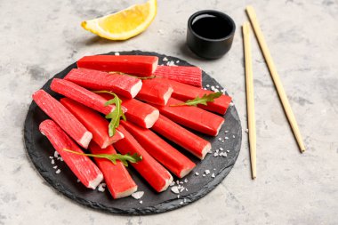 Slate board with tasty crab sticks on grunge background clipart