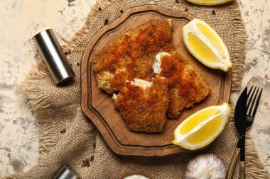 Lezzetli kızarmış morina balığının ahşap tahtası ve arkaplanda limon.