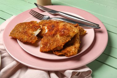 Yeşil ahşap arka planda lezzetli kızarmış morina balığı tabakları