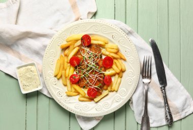 Lezzetli kızarmış morina balığı, patates kızartması ve yeşil ahşap arka planda sos.