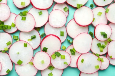 Mavi arka planda taze turp ve yeşil soğan dilimleri.