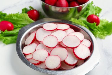 Taze turp dilimleri ve mermer arkaplanlı marul kaseleri.