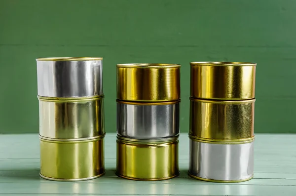Stacks of tin cans with fish on green wooden table