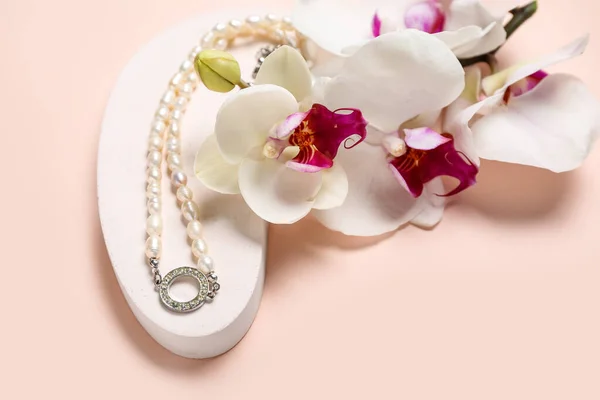 Vitrinenpodest Mit Perlenkette Und Orchideenblumen Auf Rosa Hintergrund Nahaufnahme — Stockfoto