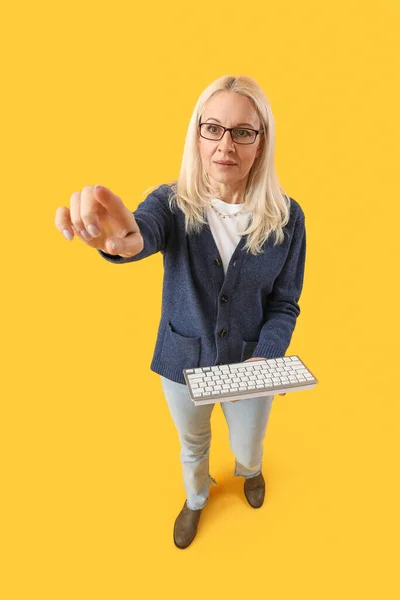 Mature Female Programmer Computer Keyboard Pointing Something Yellow Background — Stock Photo, Image