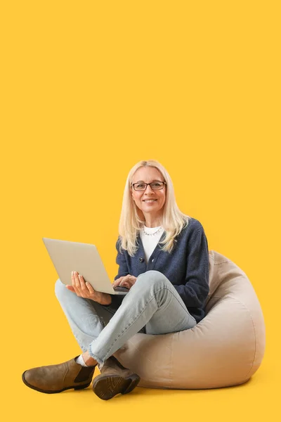Mature Female Programmer Working Laptop Beanbag Yellow Background — Stock Photo, Image